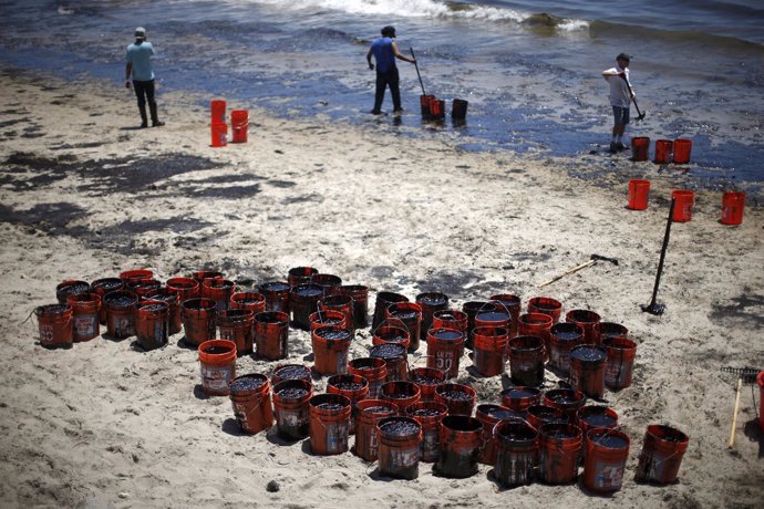 Volunteers fill buckets with oil from an oil slick along the coast of Refugio St