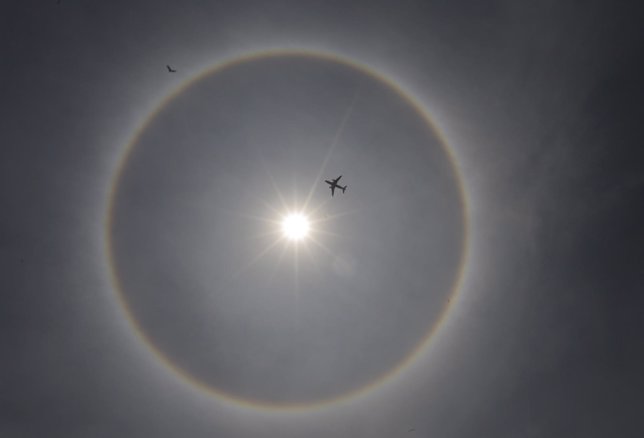 A plane flies past a solar halo in Mexico City