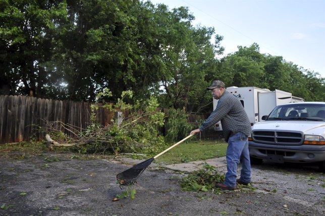 A resident of the Apollo Mobile Home Park cleans up debris left behind after a t