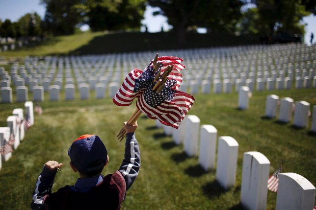 Member of the Boy Scouts of America holds flags to be placed at graves at Cypres