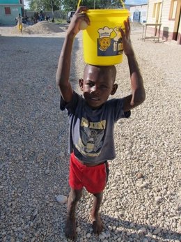 Niño con un cubo de agua en Haití