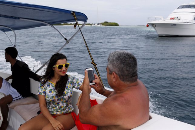 Brazilian tourists take pictures on a boat in the archipelago of Los Roques
