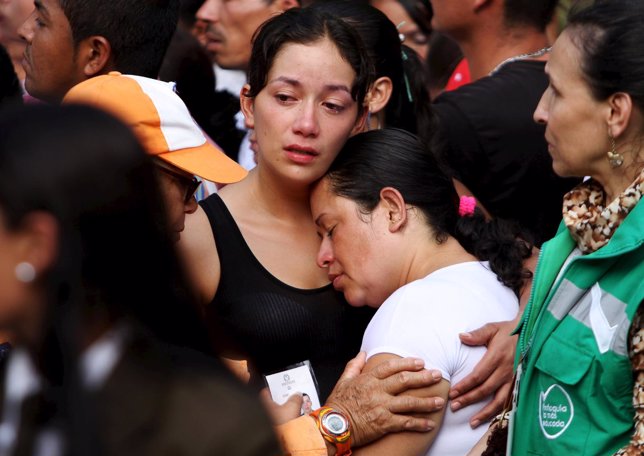 A relative mourns during a mass burial for 33 victims of a recent landslide in S