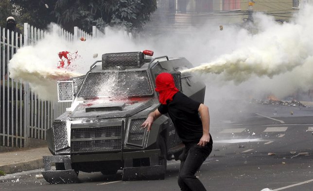 A masked student  clashes with riot police during a protest against the governme