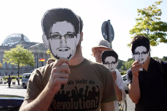 Protesters hold masks depicting former U.S. National Security Agency 