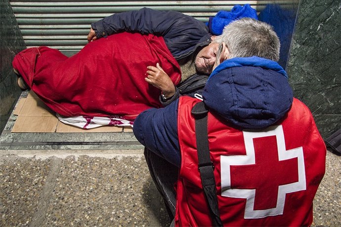 Un voluntario de CRuz Roja ayuda a una sintecho.