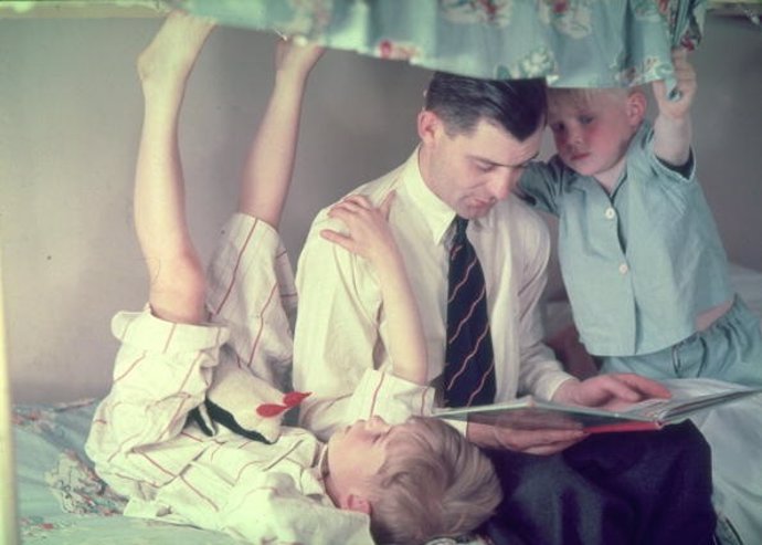Padre leyendo cuentos a sus hijos en la cama, antes de dormir