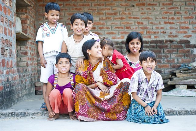Una mujer con sus dos hijos y niños vecinos en India