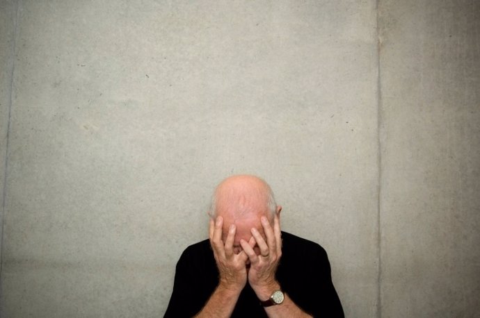 Un hombre mayor tapa su rostro, deprimido por el Alzheimer.