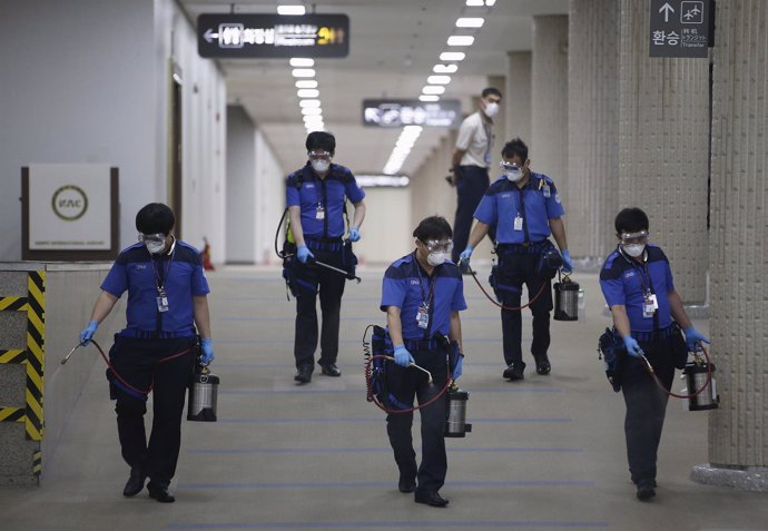 Empleados de servicios de desinfección limpian el suelo del Aeropuerto de Gimpo