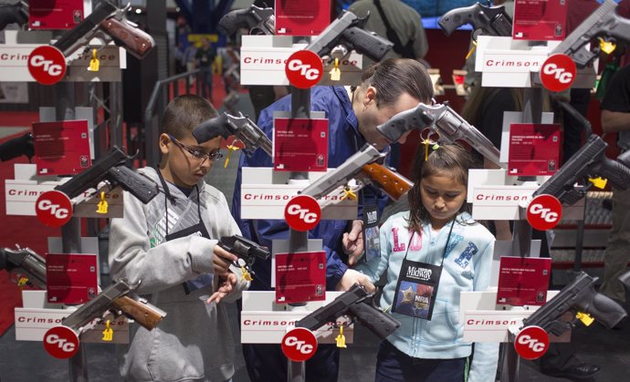 Niños examinan armas durante reunión anual de la Asociación Nacional del Rifle