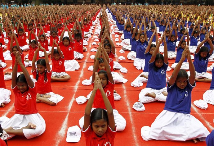 Estudiantes en clase multitudinaria de yoga