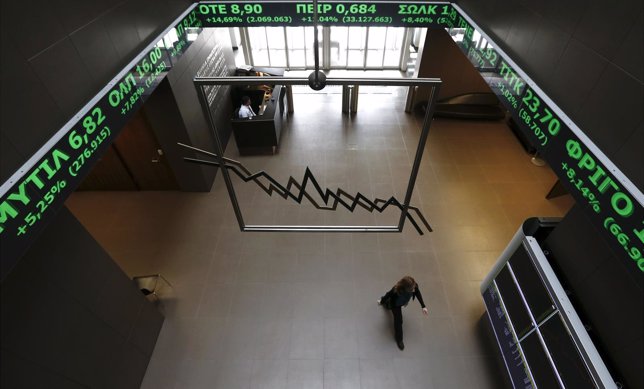 A woman walks inside the Athens stock exchange as a stock ticker shows stock opt