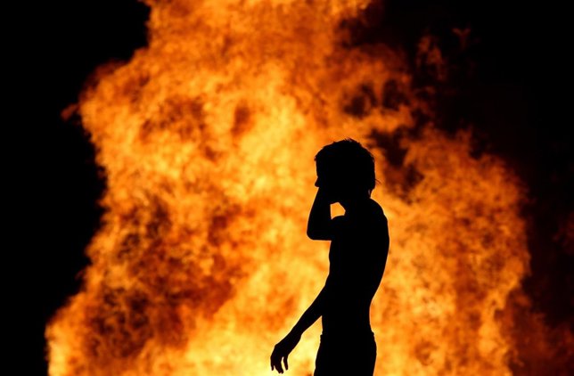 Un hombre frente a una de las hogueras de San Juan
