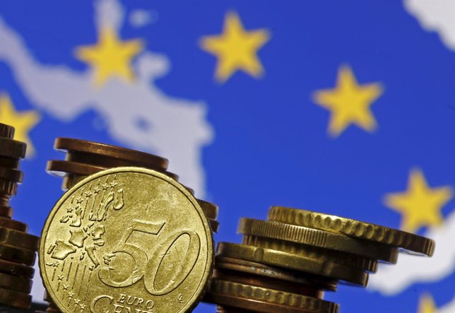 Euro coins are seen in front of displayed flag and map of European Union in this
