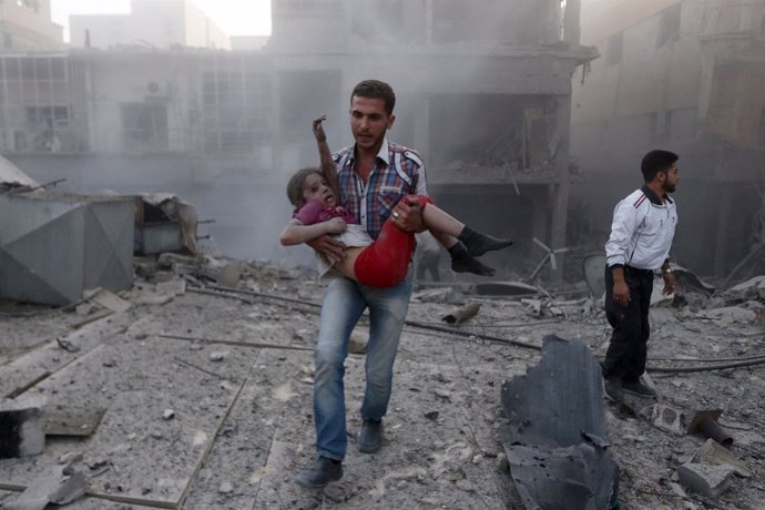 Un hombre con una niña en Siria trasun bombardeo en Damasco