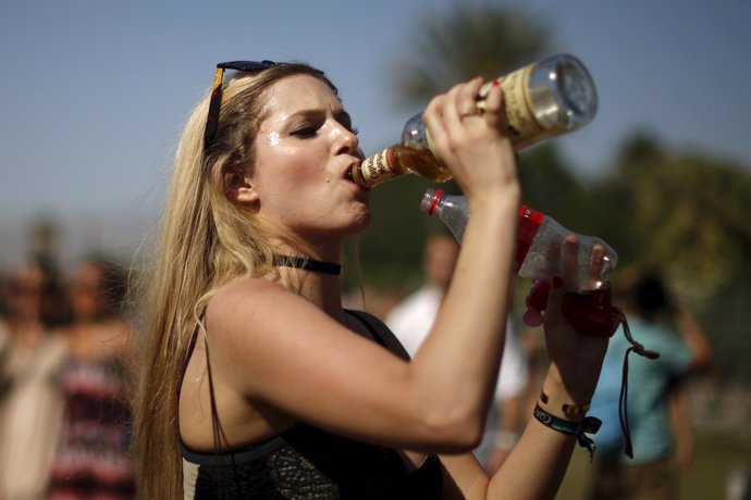 A woman swigs from bottles of rum and coke before entering the Coachella Valley 