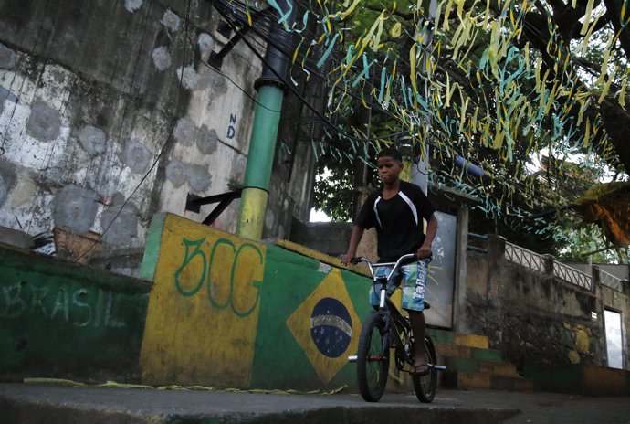 Un niño monta su bicicleta por una calle pintada con la bandera de Brasil 