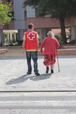 Un voluntario de Cruz Roja acompaña a una anciana