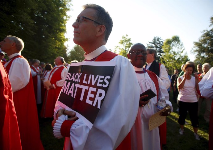 Bishop Scott Barker holds a "Black Lives Matter" sign as he along with approxima