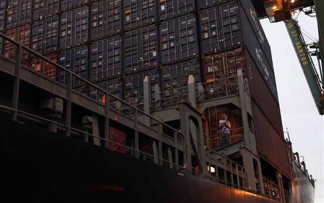Un trabajador portuario junto a una serie de contenedores ubicados en el termina