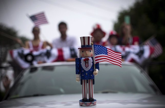 An Uncle Sam figure sits on the hood of a car in a July Fourth parade in the vil