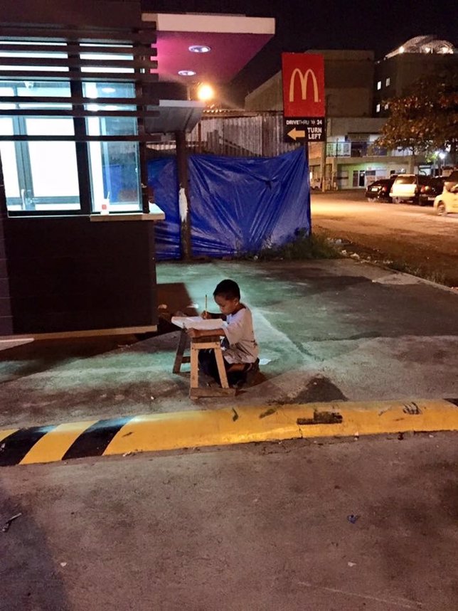 Niño estudiando bajo una luz de McDonalds