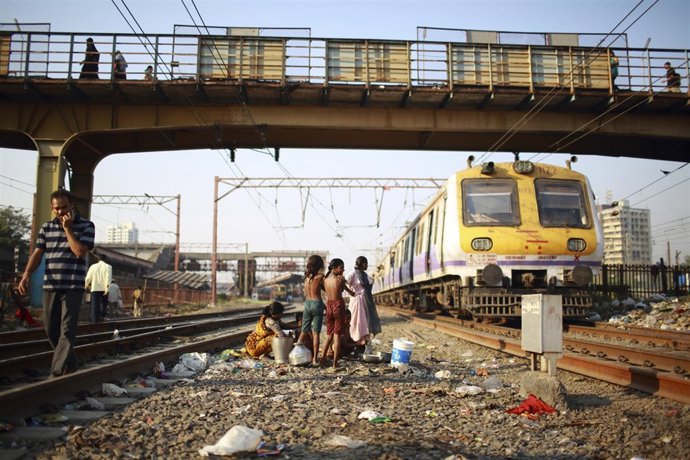 Children living in a slum next to the tracks take a bath along the railway track