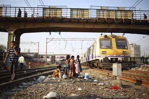 Children living in a slum next to the tracks take a bath along the railway track