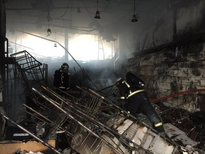 Bomberos extinguen el fuego en el local textil calcinado