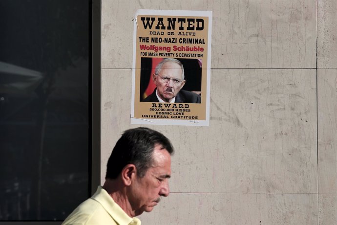 Un griego pasa por delante de un cartel con la imagen de Scheuble