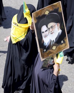 Mujer iraní sostiene una imagen de los líderes religiosos