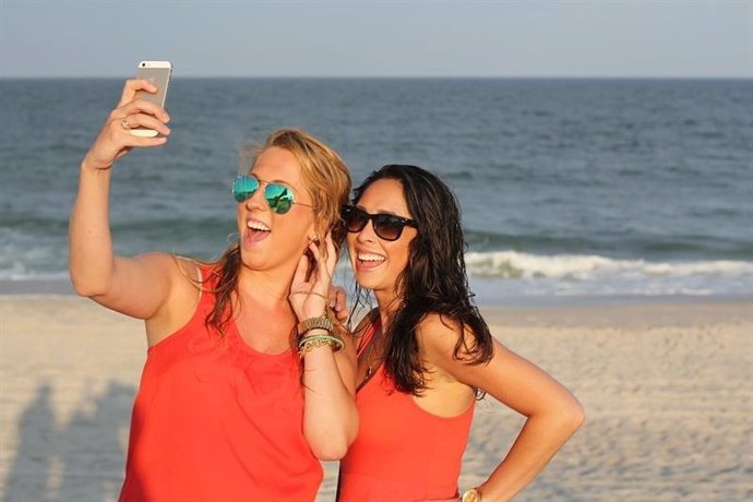 Dos amigas haciéndose un selfie en una playa