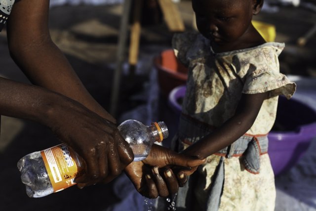 Una madre lava las manos a su hija para evitar el cólera en Sudán del Sur