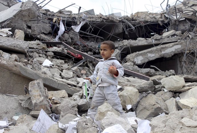 Un niño recoge juguetes entre los escombros de su casa en Yemen