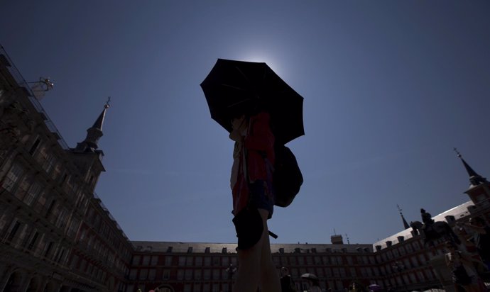 Calor. Un turista se cubre del sol con u paraguas en la plaza de sol de Madrid.