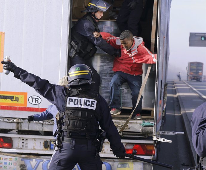 Agentes antidisturbios obligan a bajar de un camión a un inmigrante en Calais