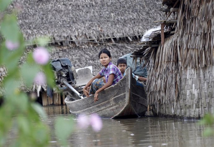 People sit on a boat near their home in a flooded village outside Zalun Township