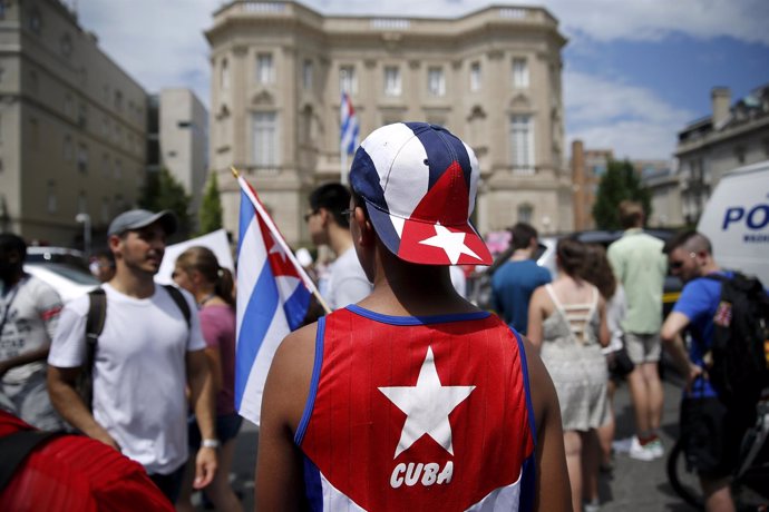 People gather outside the Cuban embassy after the Cuban flag was raised in a cer