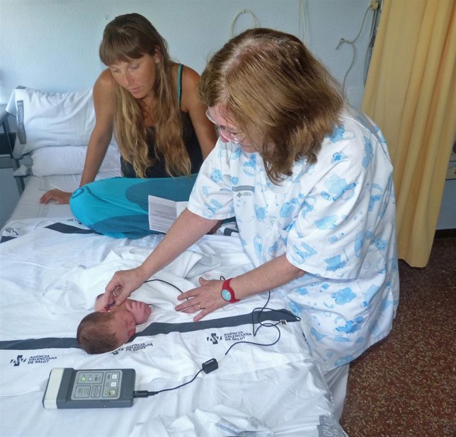 Una enfermera practica la prueba de la hipoacusia a un bebé