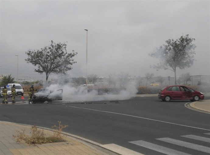 Los bomberos sofocan las llamas del coche incendiado.