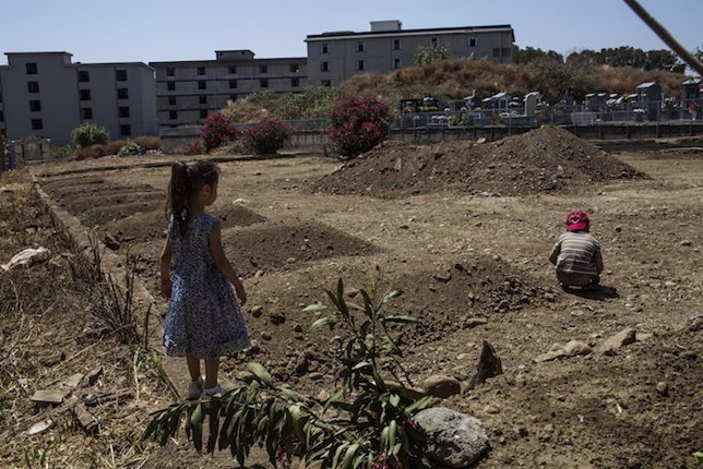 Dos niños refugiados sirios juegan junto a la tumba de su abuela en Catania