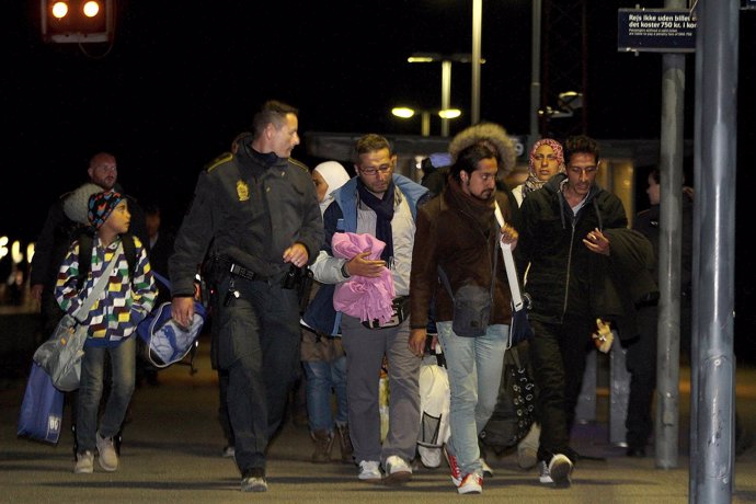 Refugiados escoltados por la Policía tras llegar a Dinamarca