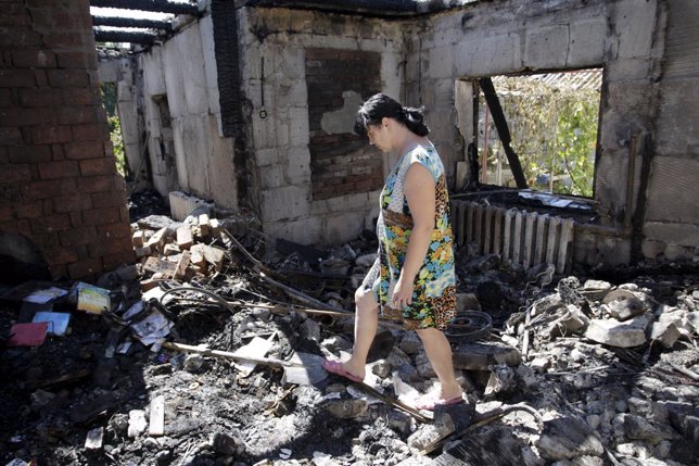 Una mujer camina entre los escombros de una casa en Donetsk (Ucrania)