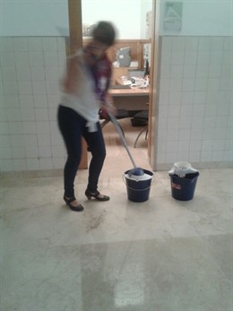 Un trabajadora de la UA intenta secar una zona de despachos en el rectorado