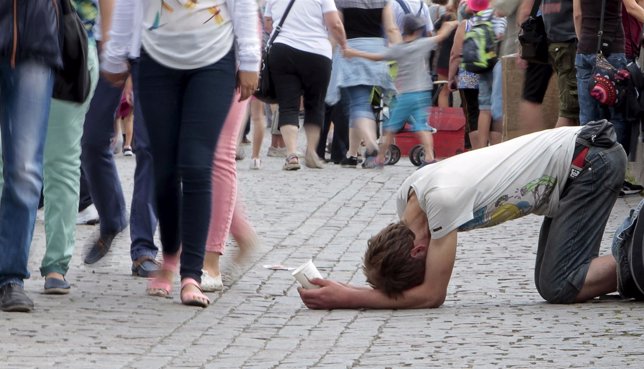 Turistas pasan delante de un mendigo en Praga