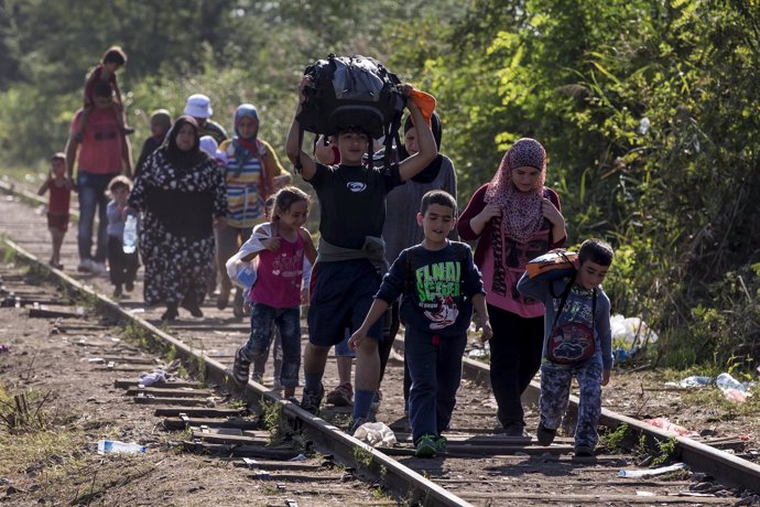 Refugiados andando por la via del tren