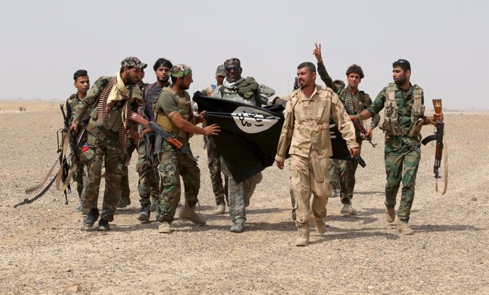 Militantes del Estado Islámico portan una bandera del Estado Islámico