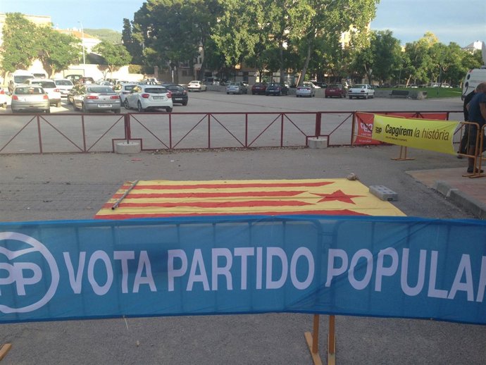 Pancarta del PP junto a una estelada ante el mismo lugar de un mitin de PP y CUP