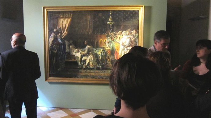 Una visitante observa la obra de Pinazo mientras las autoridades conversan